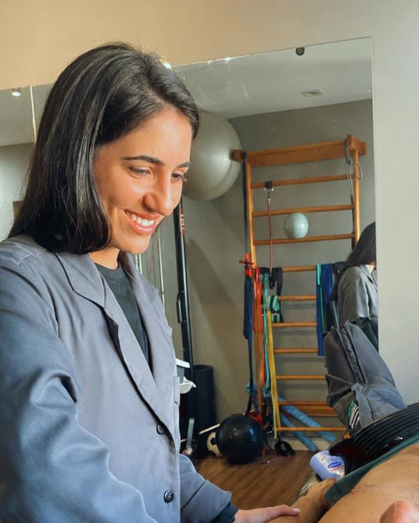 Júlia Martuscello, fisioterapeuta, sorrindo durante um atendimento de fisioterapia